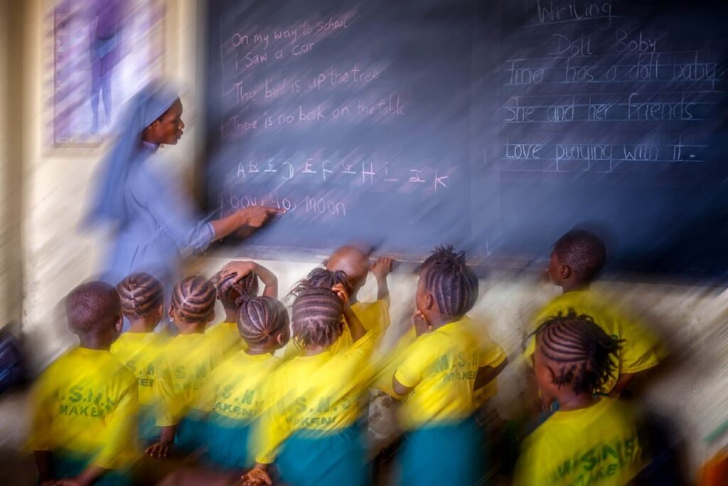 Foto 3 _"La classe di Makeni" racconta il futuro dei bambini che ascoltano una monaca alla lavagna, in una stanza semplice dove la conoscenza diventa possibilità. È un’immagine che parla di educazione come atto rivoluzionario. - Nuova Genesi Sierra Leone (Portfolio di Sebastiano Cosimo Auteri)